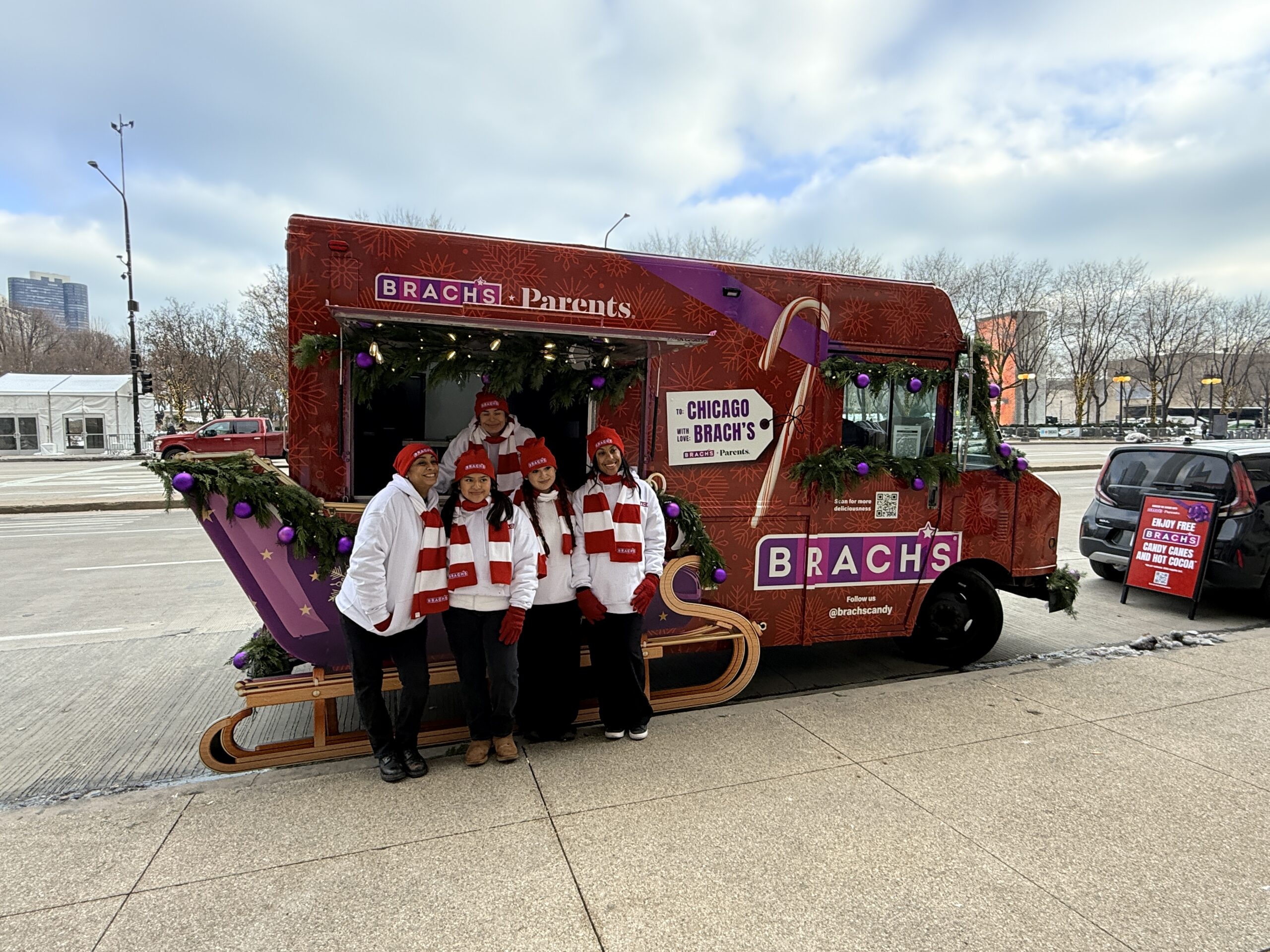 Brach’s holiday branded food truck with brand ambassadors posing in front of the mobile candy sampling activation.