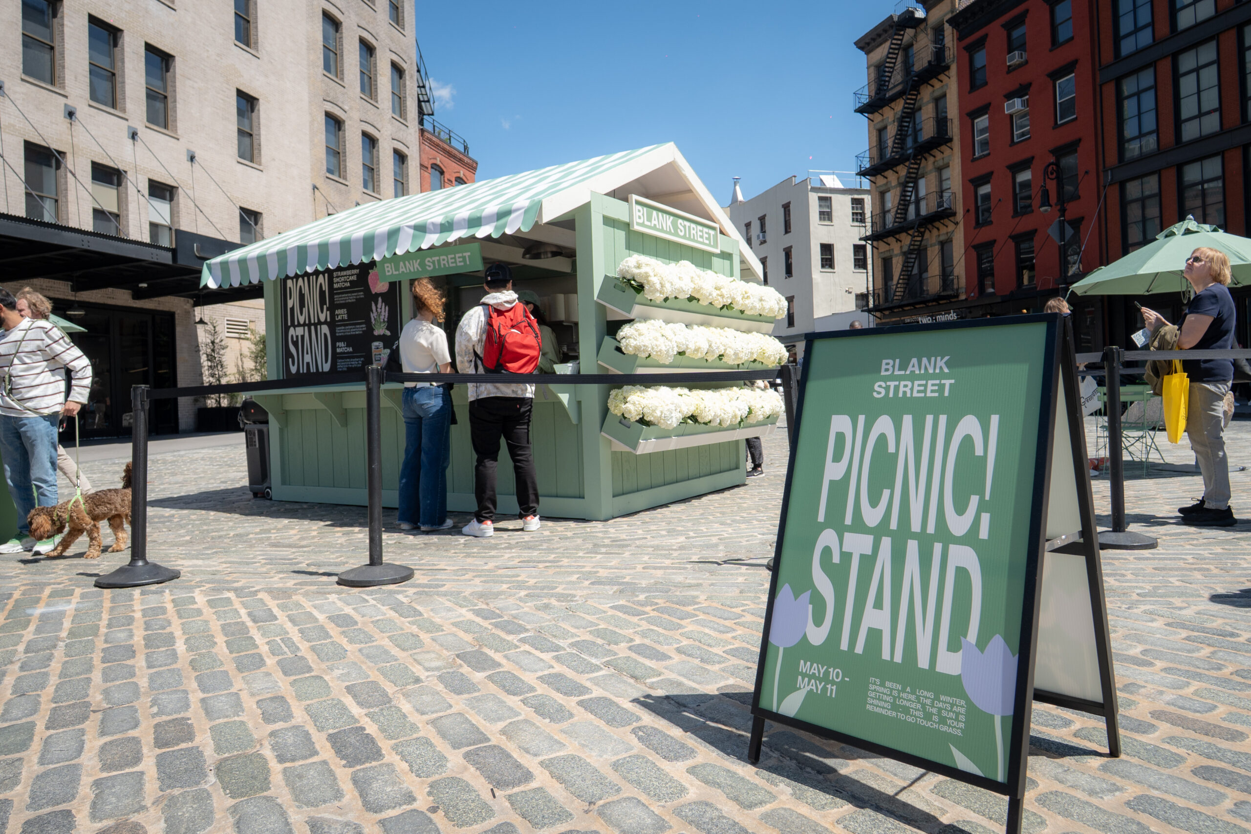 Blank Street custom picnic stand kiosk with branded signage and guests visiting the outdoor matcha sampling activation.