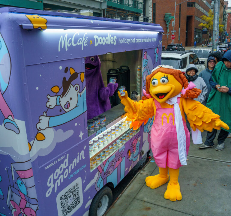 McCafé and Doodles branded food cart with a mascot, product display, and customers waiting in line.