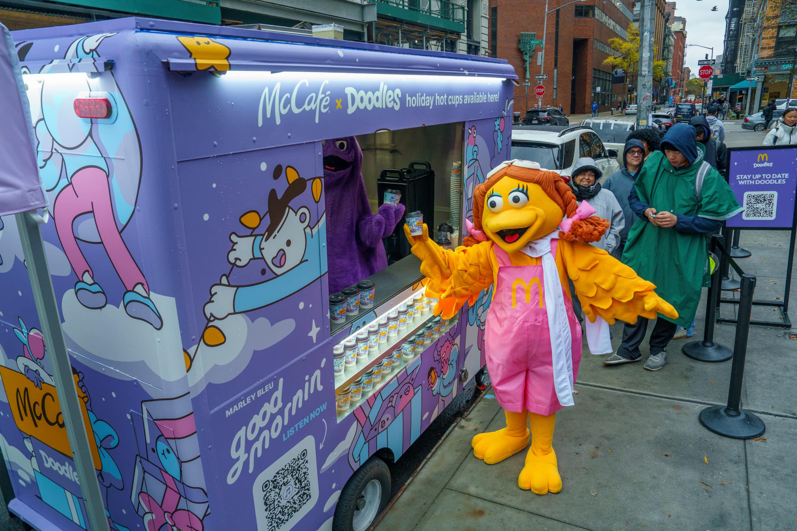 McCafé and Doodles branded food cart with a mascot, product display, and customers waiting in line.