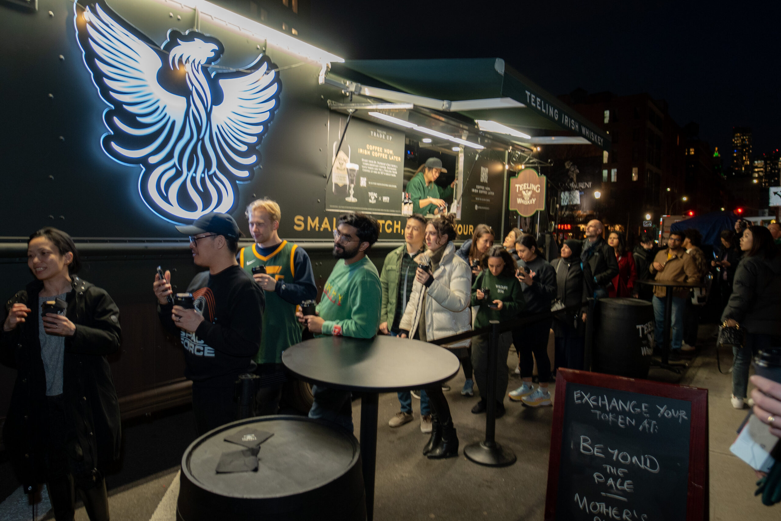 Guests gathered at a dark mobile activation featuring a large phoenix graphic.
